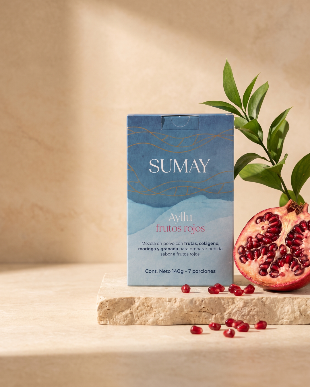 Una caja de Ayllu frutos rojos sobre una mesa junto a una fruta de granada.
